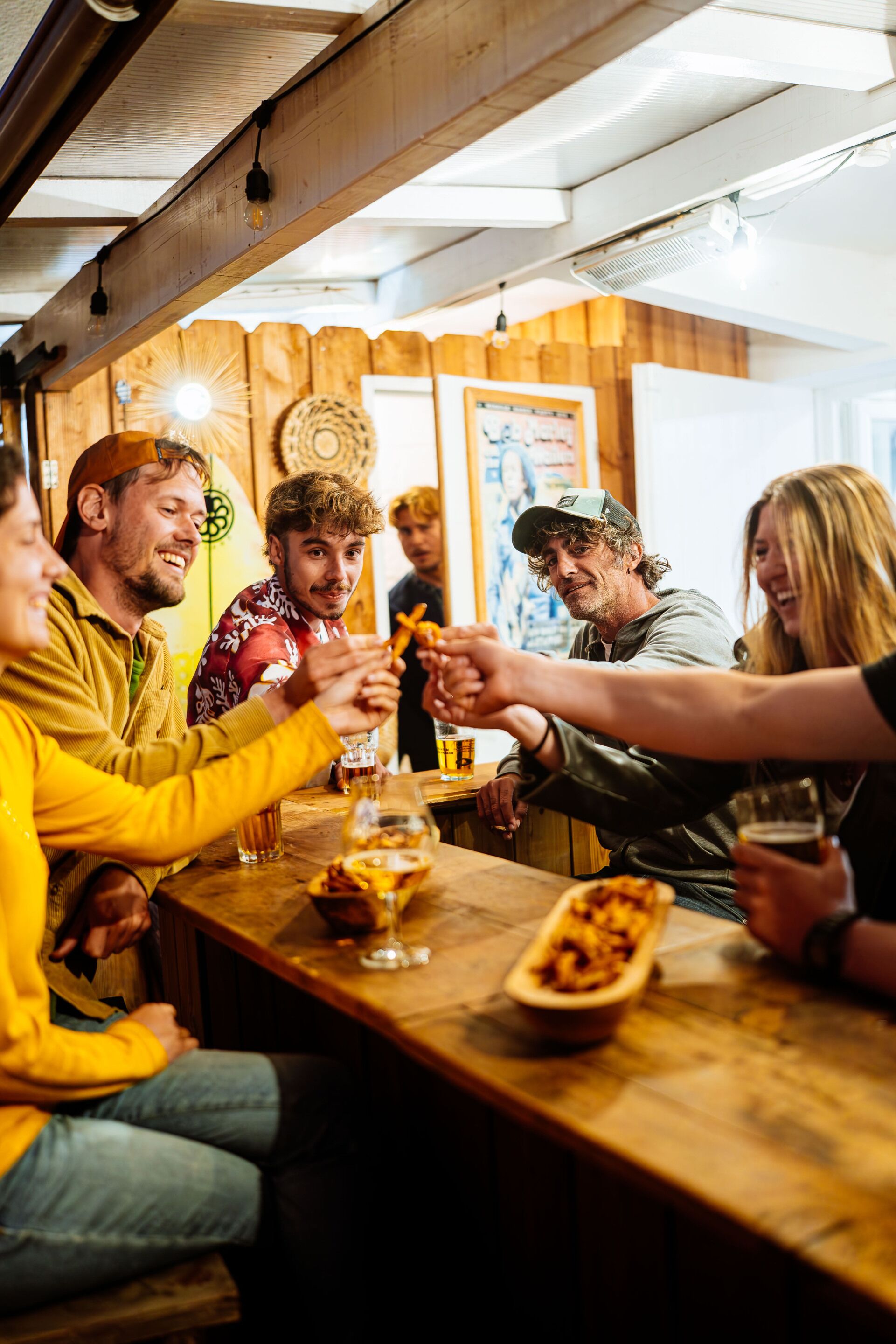 Un groupe de personnes est assis autour d’une table en bois, et chacun a devant soi des collations et des boissons.