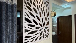 Ein modernes Interieur mit einer dekorativen weißen Wandverkleidung, einer Bank, einer Uhr und einem durch eine Tür erkennbaren Badezimmer.