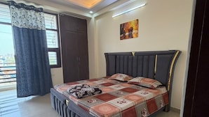 Ein Schlafzimmer mit einem Bett, einem Deckenventilator, einem Fenster mit Vorhängen und einem Bild an der Wand.