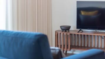 Una sala de estar moderna con un sofá, un televisor sobre un mueble de madera y un cuenco decorativo.