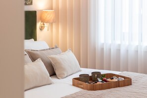 Habitación de hotel con cama, almohadas, bandeja con alimentos para el desayuno y ventana con cortinas.