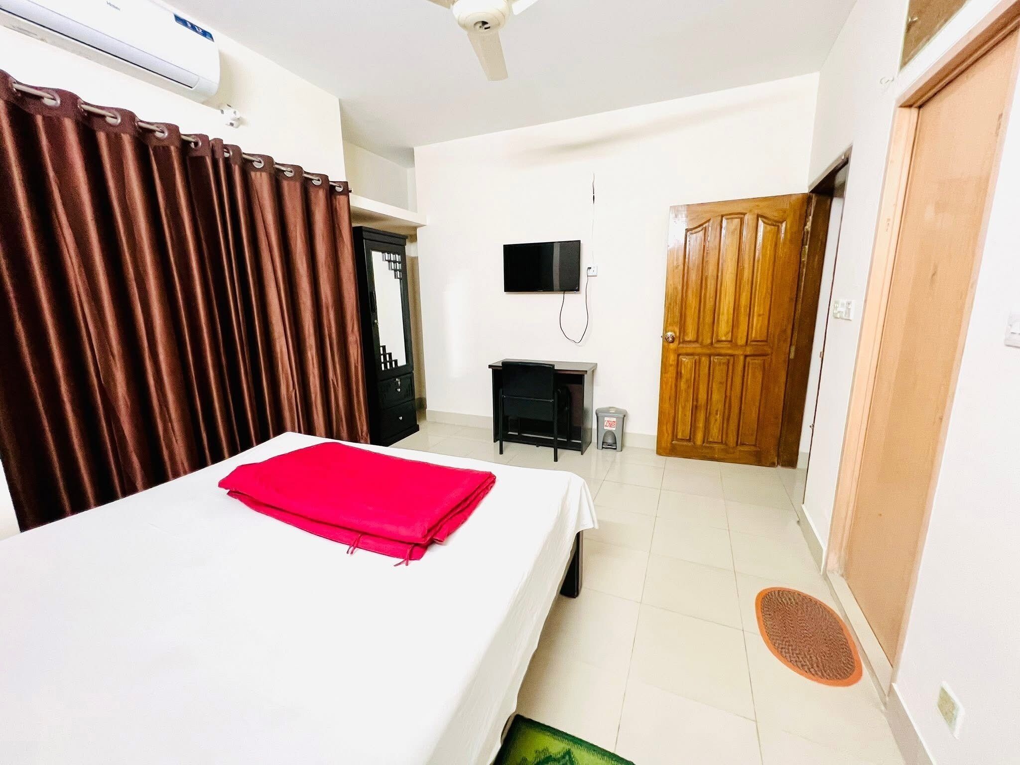 Un dormitorio con cama, televisión, armario y puerta.