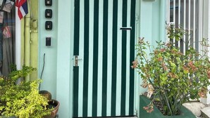 Un edificio con una puerta verde y blanca a rayas, un letrero con el número '171' arriba y una pequeña bandera.