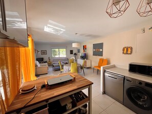 A modern kitchen with a washing machine, a dining area with a table and chairs, and a living room with a sofa and a TV. - Apartment Cavalaire center near beaches 75 m2 garden floor beautiful terrace (Cavalaire-sur-Mer)