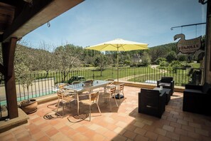 Eine Terrassensitzgelegenheit mit Tisch und Stühlen, einem gelben Sonnenschirm und einem Schild für PFAJOLLE.