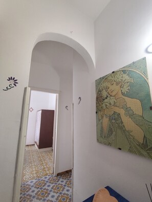 An interior hallway with an arched doorway, a patterned floor, and a wall-mounted artwork.