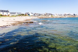 Eine Küstenstadt mit klarem Wasser, Sandstrand und Häusern entlang der Uferlinie.