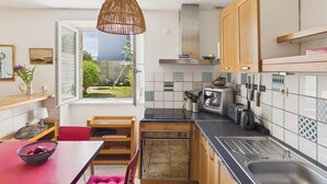 A kitchen with wooden cabinets, a black countertop, a sink, a toaster, and a hanging light fixture. - Family home for 5, garden - La Torche (Plomeur)