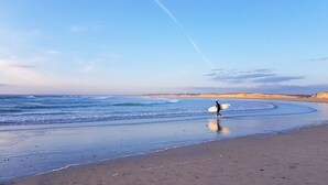 A beach with a person carrying a surfboard. - Family home for 5, garden - La Torche (Plomeur)