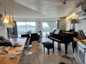 A modern living room with a piano, dining area, and a view of the outdoors. - House right on the beach in Arzon Port Navalo (Arzon)