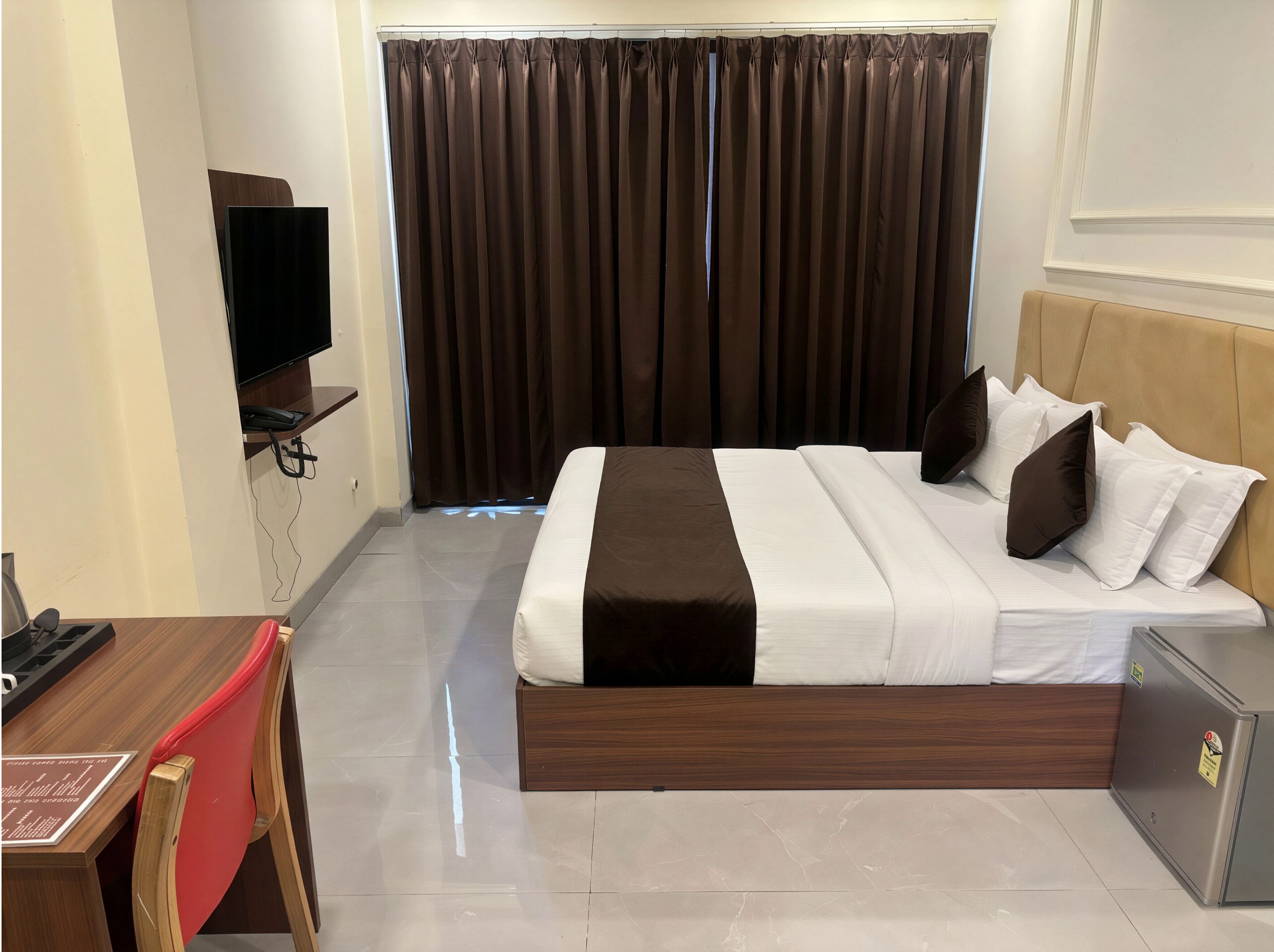A hotel room with a bed, a desk, a chair, a television, and a wardrobe.