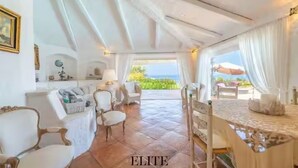 Un'ampia stanza con soffitto alto, zona pranzo con tavolo e sedie, e vista sull'esterno.