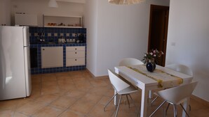 A kitchen with a white refrigerator, blue tiled backsplash, and a dining table with chairs. - Didimos Resort (Montebello Ionico)