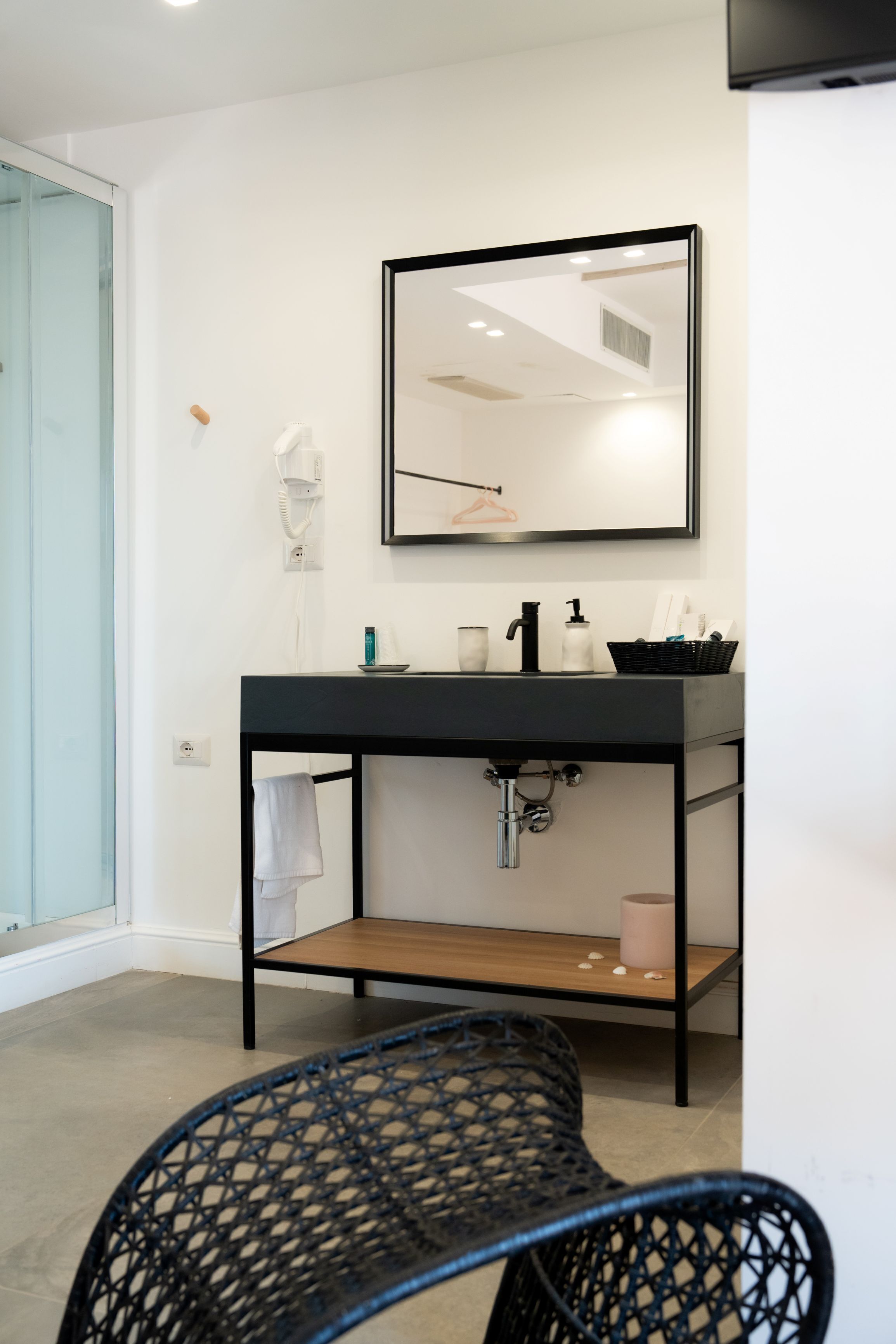 A modern bathroom with a black vanity, a mirror, and a towel rack.