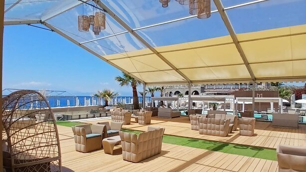 An outdoor deck with seating and a canopy, overlooking a coastal area. - Didimos Resort (Montebello Ionico)