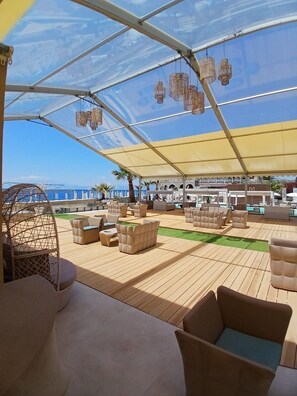An outdoor deck with seating and a canopy, overlooking a coastal area. - Didimos Resort (Montebello Ionico)
