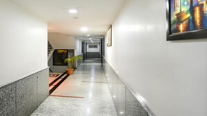 Un corridoio con pavimento in marmo, un quadro incorniciato e una pianta in vaso.