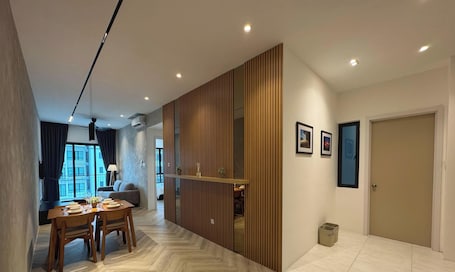 A modern hotel room with a dining area, a sofa, a wooden partition, and a door.. Rumahõ - Upton By Elica