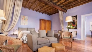 Um quarto aconchegante com sofá, cadeiras de vime, um armário de madeira e um espaço de refeições.