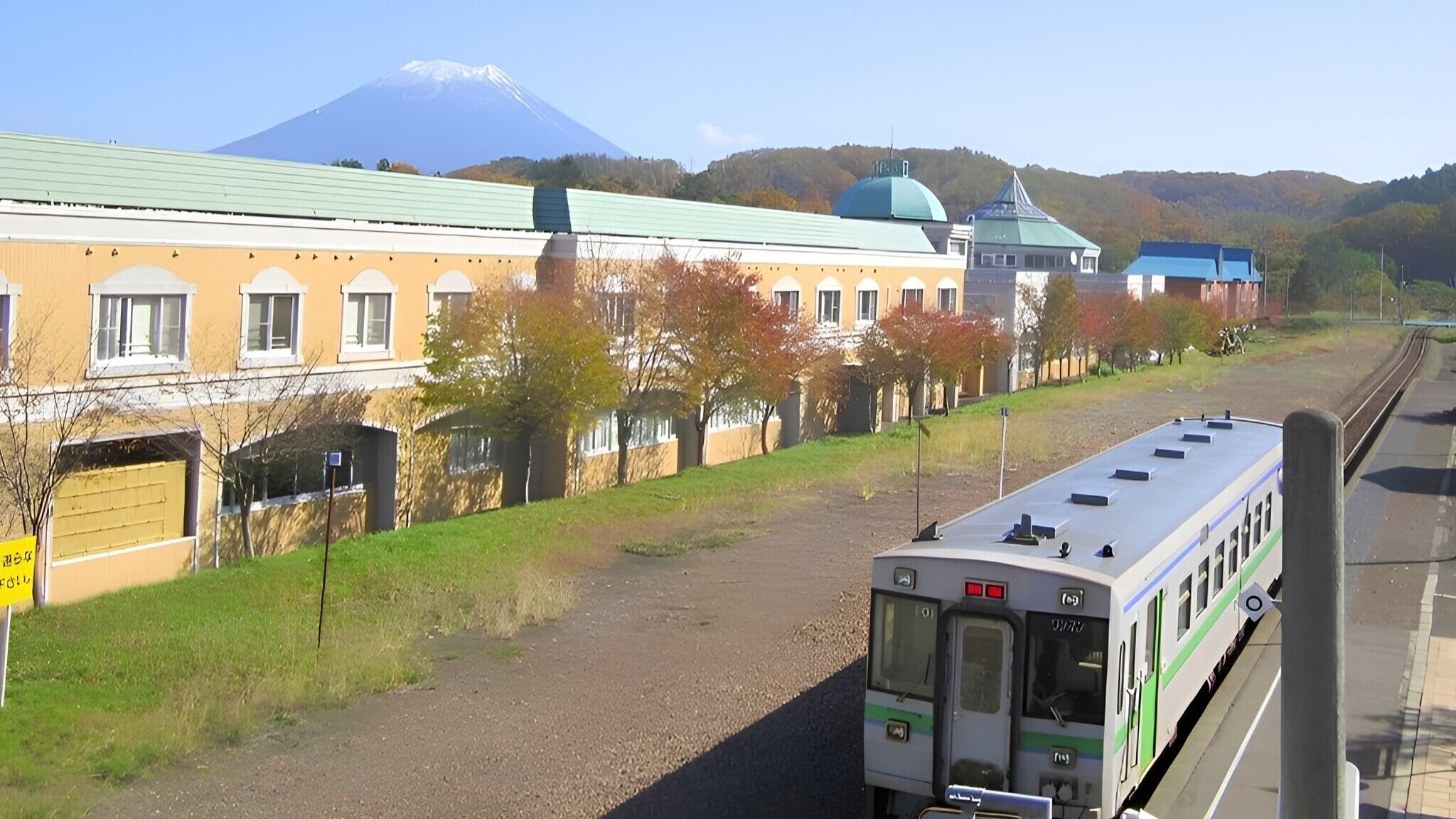 A train station with a building featuring a green dome and a mountain in the background.