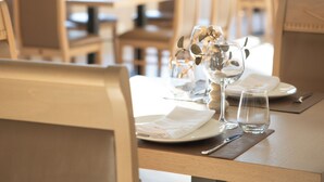 A restaurant with tables set for dining, chairs, and a view through large windows. - Koral Boutique Hotel & Bistro (Durrës)