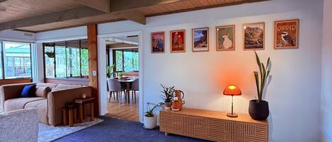 A spacious living area with a wooden ceiling, a sofa, a coffee table, a lamp, and wall art.