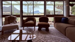 A room with a large window, a sofa, two armchairs, a coffee table, and a hanging plant. - Southern Grampians Lookout (Dunkeld)