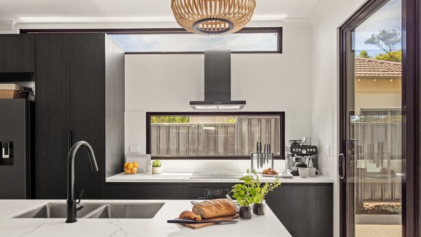 Une cuisine moderne dotée d’un îlot central, d’un four encastré et d’une grande fenêtre.
