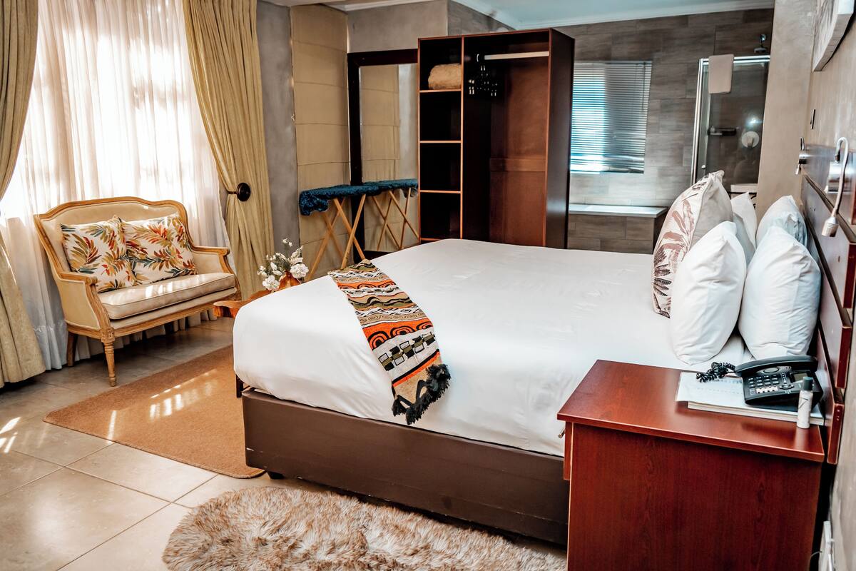 Hotelkamer met een bed, een nachtkastje van hout, een stoel, een garderobe en een douchehoek.
