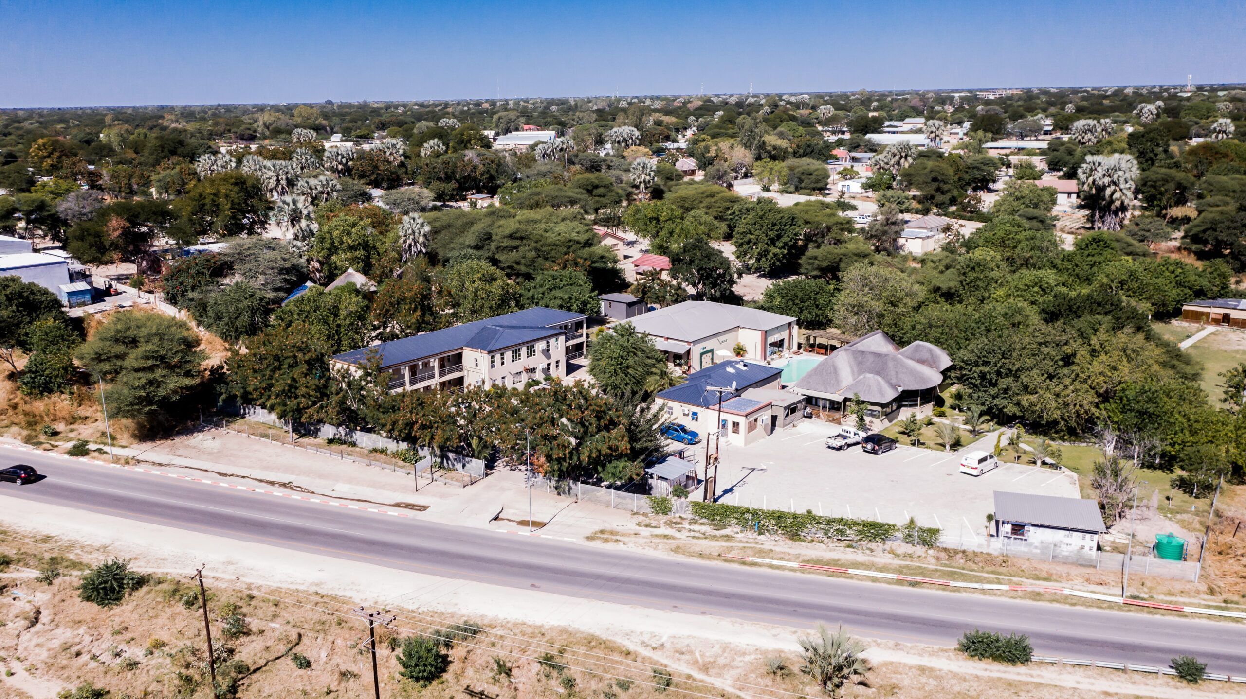 A residential area with houses, a road, and surrounding greenery.