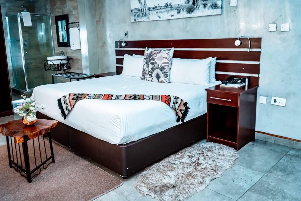 Een moderne hotelkamer met een groot bed, nachtkastje en een klein bureau.