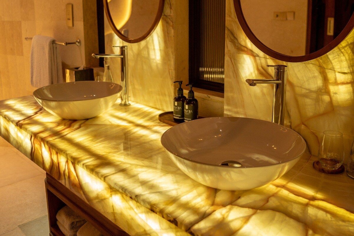 A bathroom with two sinks, a mirror, and pendant lighting.