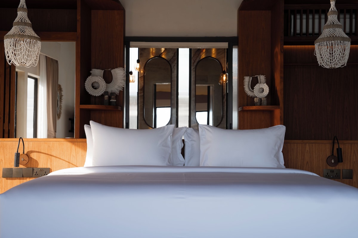 A large bed with white linens, wooden headboard, and bedside lamps.