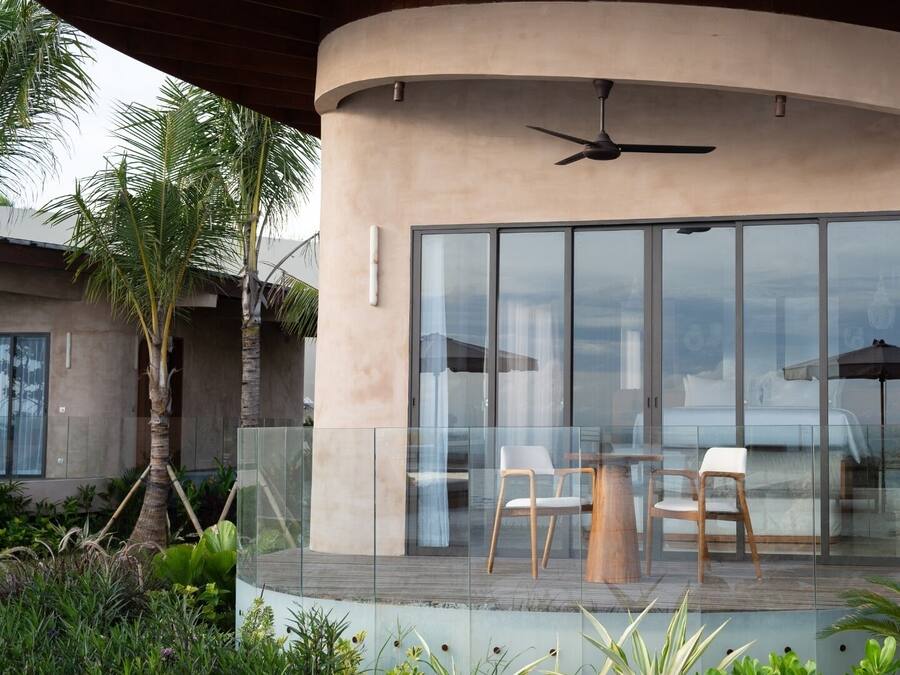 A modern building with a curved facade, large glass windows, and a ceiling fan.