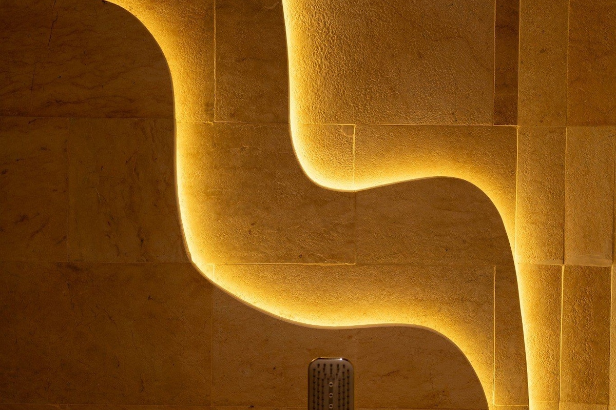 A bathroom with a unique curved wall design and a modern faucet.