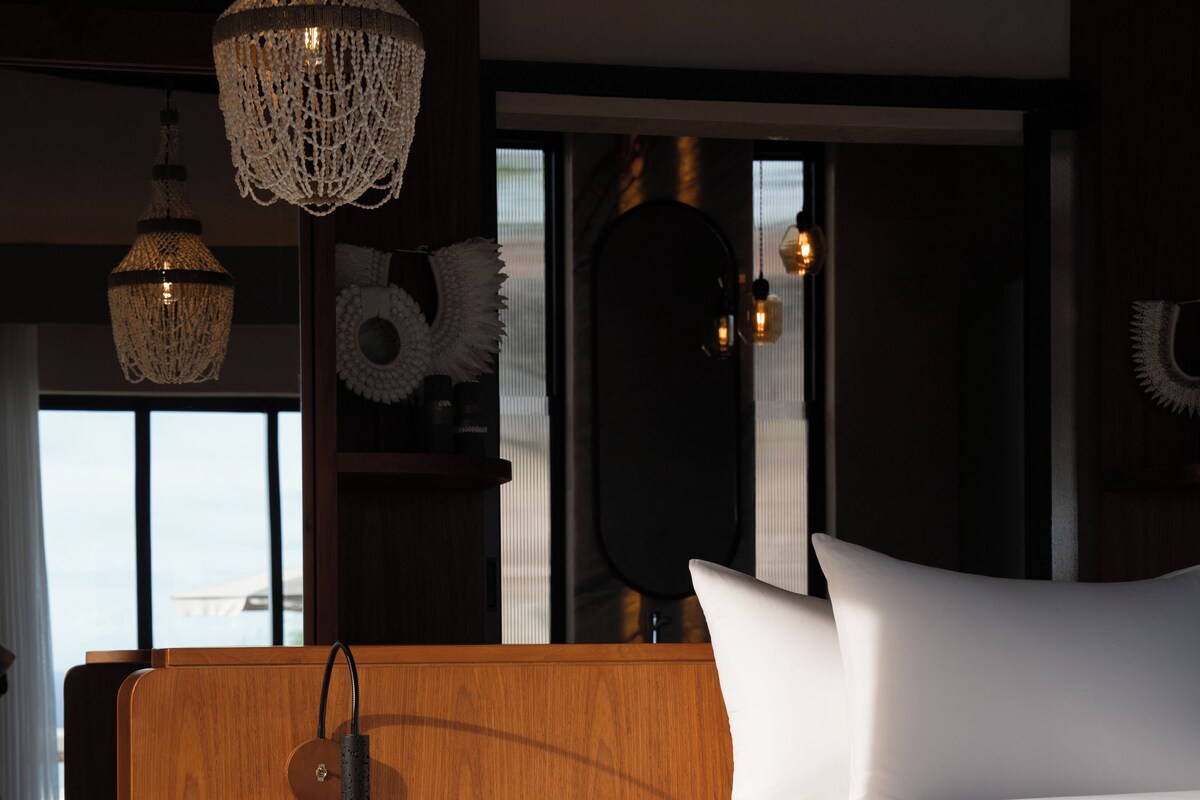 Un dormitorio moderno con cabecera de madera, una cama grande, un inodoro integrado y un ventanal con vistas.