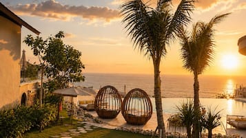 Un resort con piscina, palmeras y vistas al atardecer.