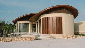 A modern building with a curved roof, large windows, and a stone wall. - VANARA Resort & Spa (Pecatu)