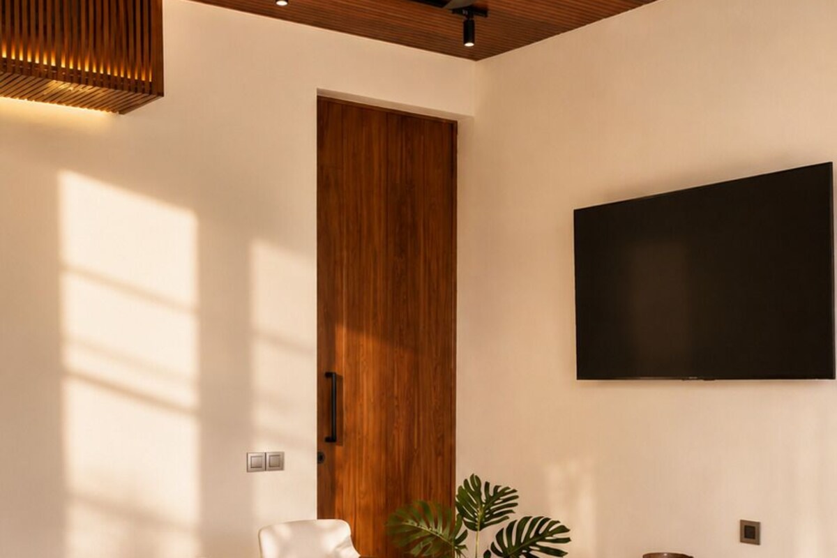 A modern living room with a sofa, chairs, a coffee table, a TV, and a ceiling fan.