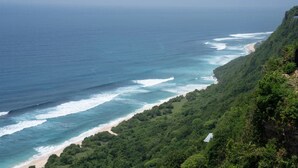 A coastal landscape with a beach, ocean waves, and dense green vegetation. - VANARA Resort & Spa (Pecatu)