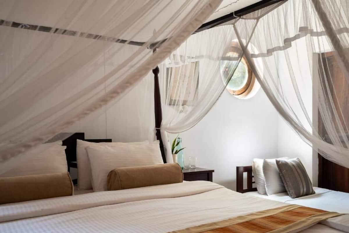 A bedroom with a canopy bed, a bedside table, and a nightstand.