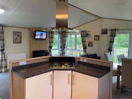 Una cocina compacta con una isla central, un televisor y vistas al exterior.
