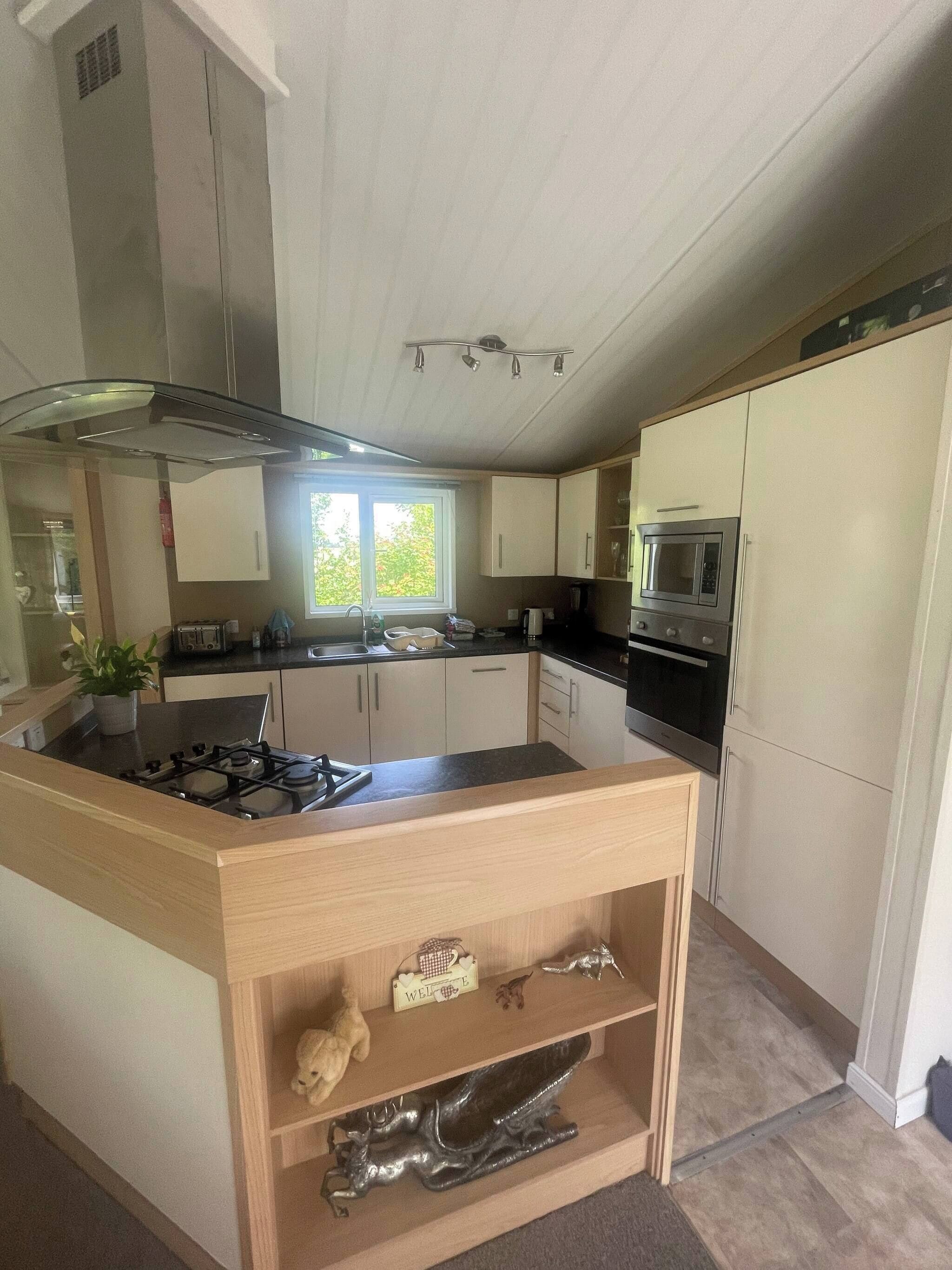 A modern kitchen with a central island, stainless steel appliances, and a view of the outdoors.