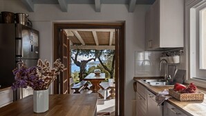 Una cucina con vista sull'esterno, un tavolo di legno e un frigorifero.