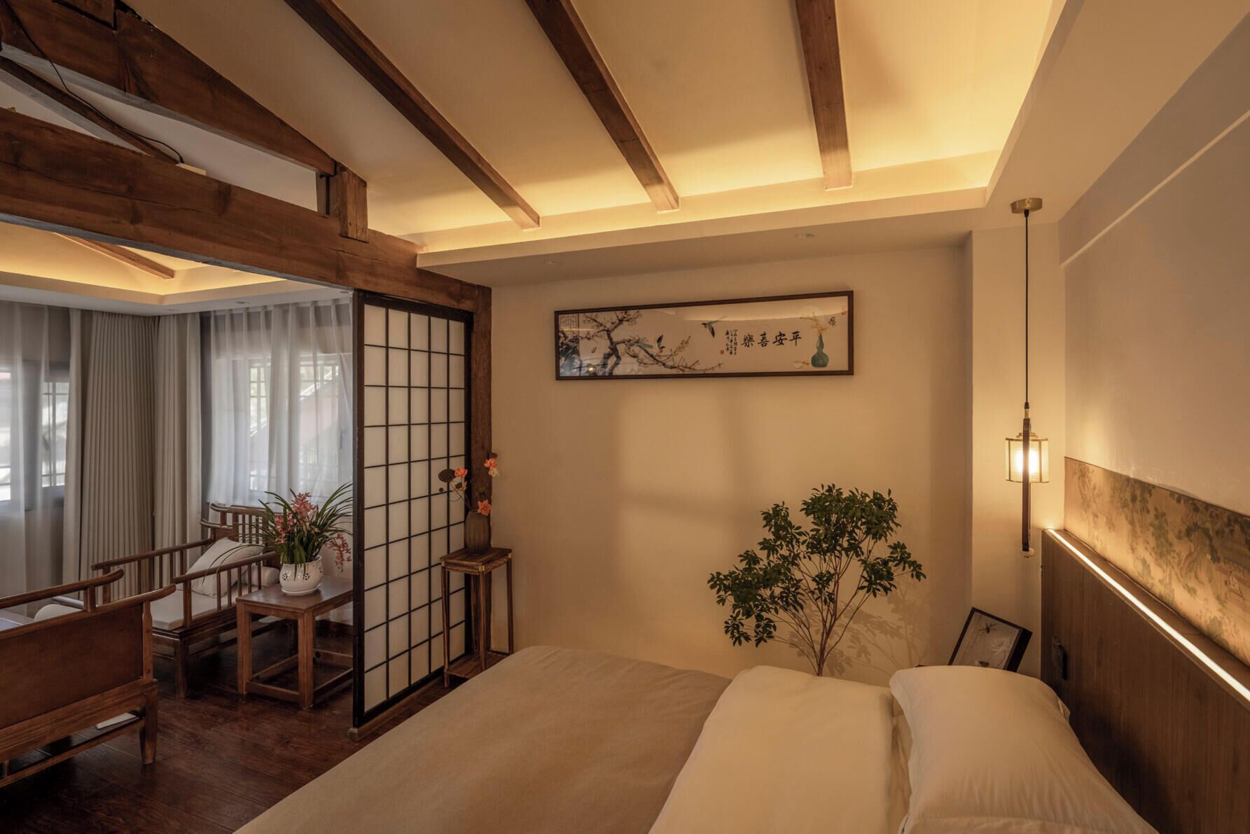A traditional Japanese-style room with tatami flooring, a low wooden bed, a shoji screen door, a desk with a chair, and a hanging lamp.