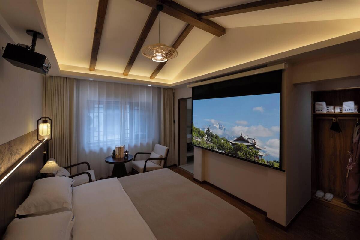 Une chambre d’hôtel avec un grand lit, un bureau avec une chaise, une télévision et une vue sur un paysage montagneux.