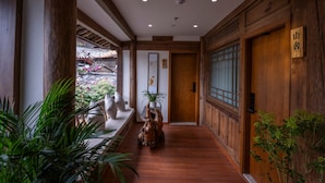 Un pasillo con paredes y puerta de madera, y un letrero con caracteres japoneses.