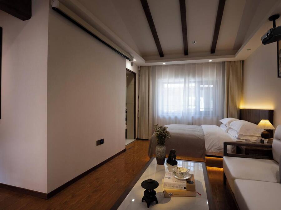 A hotel room with a bed, a sofa, a coffee table, and a painting on the wall.