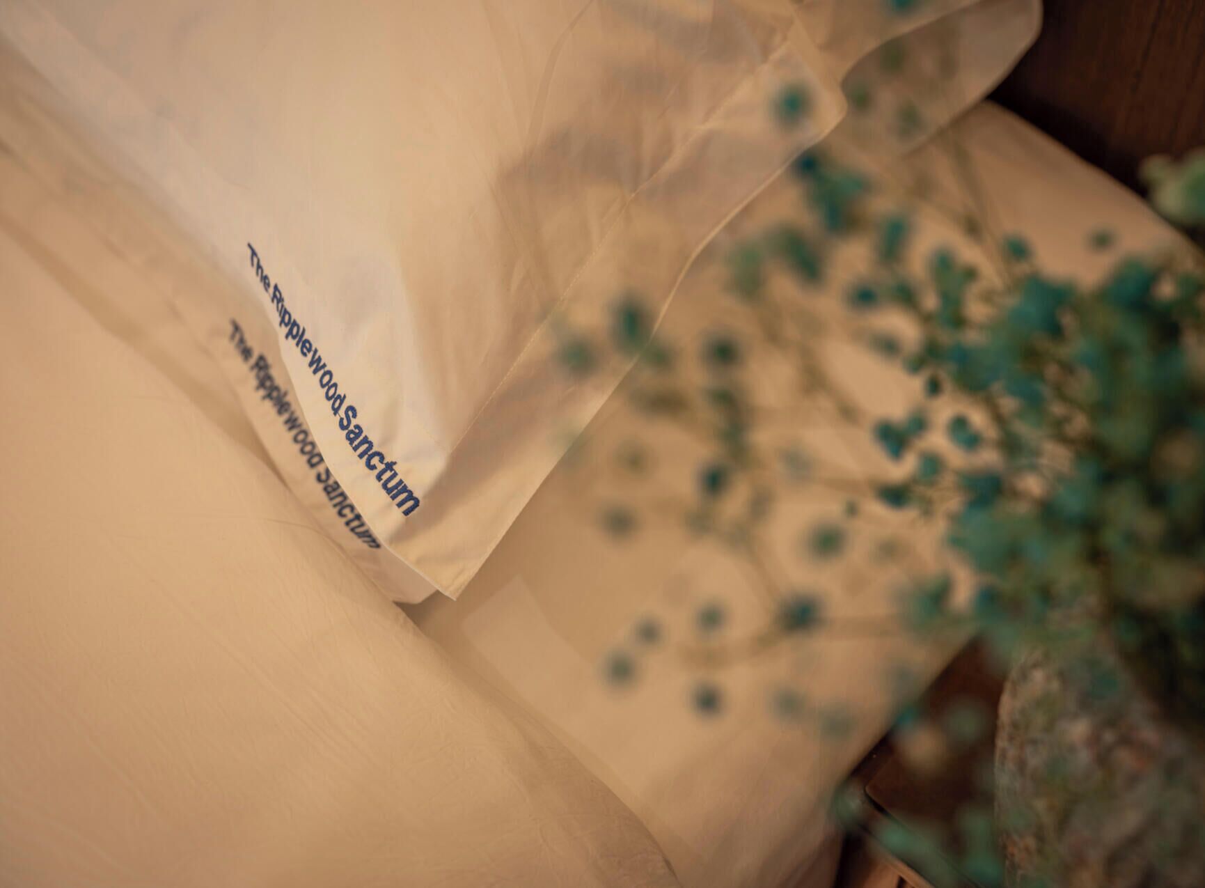 A white pillow with text and a blurred background with green flowers.