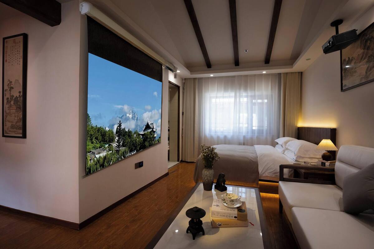 Une chambre d’hôtel avec une grande fenêtre, un lit, un canapé, une table basse et un téléviseur.